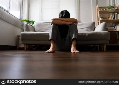 Man with mental health problem sitting on floor to resting head on his arms with depressed emotion.
