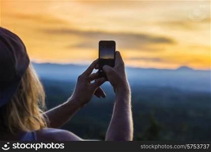 Man with Mobile Phone and Volcano Agung as Background.at Sunrise Time,Bali,Indonesia.