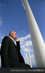 Man with mobile phone next to wind turbines