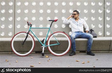 Man with mobile phone sitting on a bench in the park ( lifestyle )