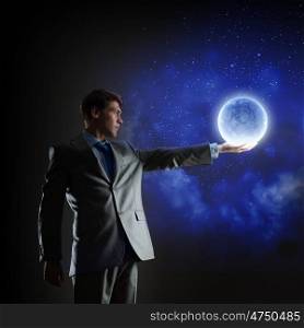 Man with moon. Young man in suit holding moon in palm