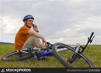 Man with mountain bike in a meadow talking on mobilel phone