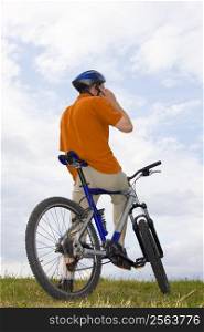 Man with mountain bike on a meadow making a phone call