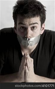 Man with mouth covered by masking tape preventing speech.