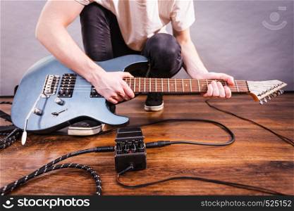Man with musical instrument setting up guitar audio stomp box effects and cables in music studio. Man setting up guitar equipment