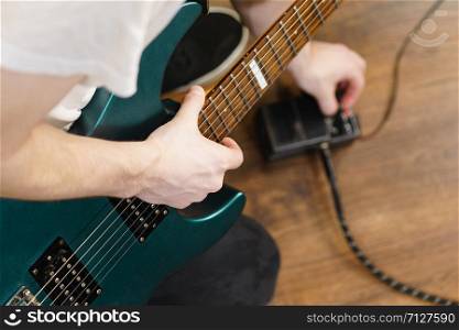 Man with musical instrument setting up guitar audio stomp box effects and cables in music studio. Man adjusting guitar effects pedal