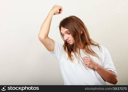 Man with odor of sweat . Expression of very bad smell. Young long haired sweaty man making hand gesture. Sweating concept.