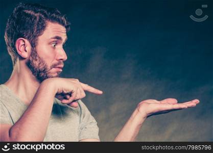 Man with open empty hand palm for copy space.. Portrait of handsome man with open empty hand palm for copy space. Young guy in studio on black. Advertisement. Instagram filter.