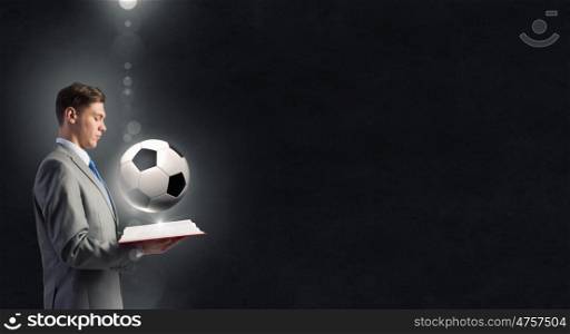 Man with opened book. Young businessman with book in hands and soccer ball on pages