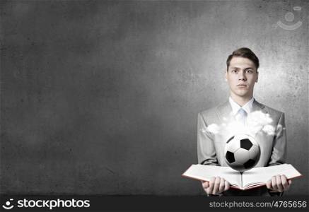 Man with opened book. Young businessman with book in hands and soccer ball on pages