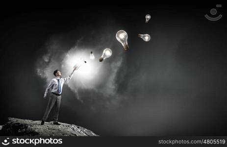 Man with opened book. Young screaming businessman on pile reaching hand with opened book and light bulb flying out