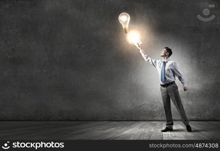 Man with opened book. Young screaming businessman on pile reaching hand with opened book and light bulb flying out