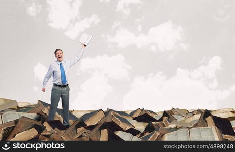 Man with opened book. Young screaming businessman on pile reaching hand with opened book