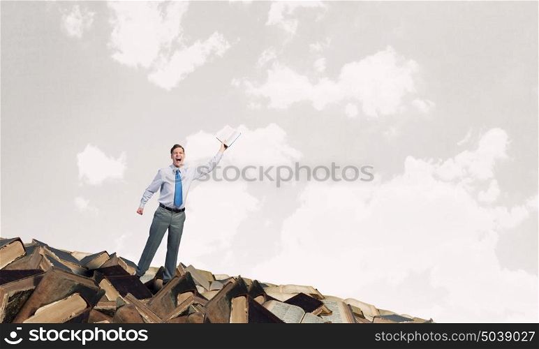 Man with opened book. Young screaming businessman on pile reaching hand with opened book