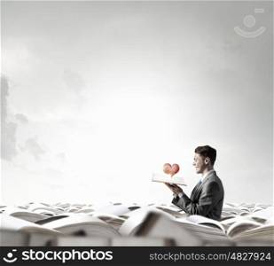 Man with opened book. Young shocked businessman with opened book in hand and red heart on pages