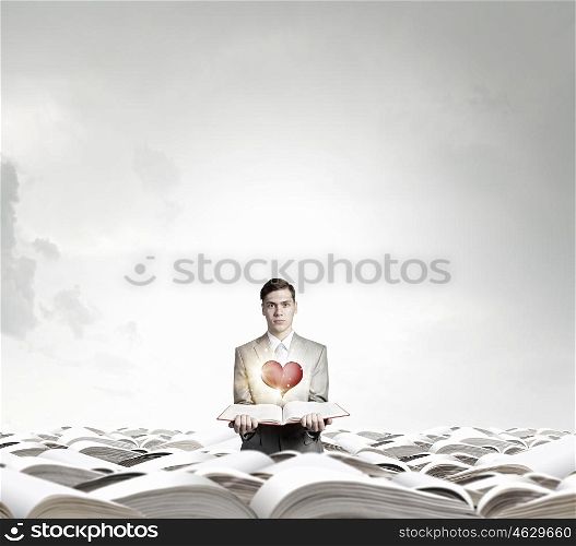 Man with opened book. Young smiling businessman with opened book in hand and red heart on pages