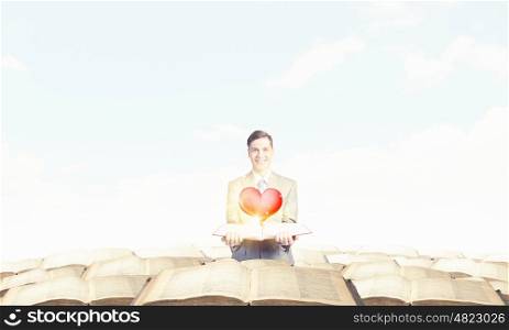 Man with opened book. Young smiling businessman with opened book in hand and red heart on pages