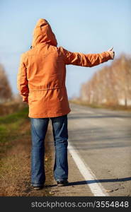 man with orange coat on the empty road, selective focus