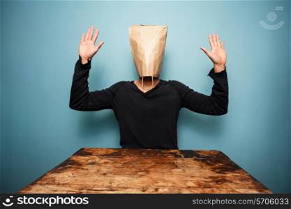 MAn with paper bag over his head with his hands up