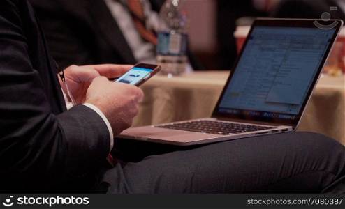 Man with phone and laptop at a conference