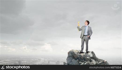 Man with phone receiver. Smiling businessman talking on yellow phone handset on rock top
