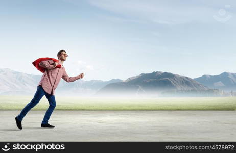 Man with red bag. Young man in casual carrying heavy red bag