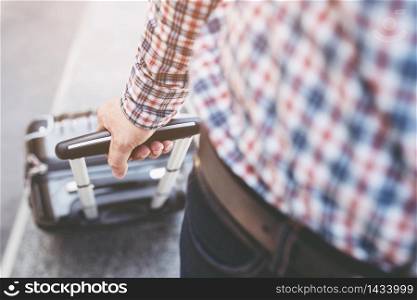 Man with shoulder bag and hand luggage walking in airport