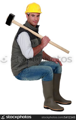Man with sledge-hammer sat on stool