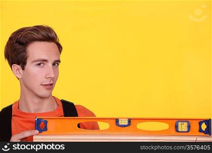 Man with spirit level on yellow background