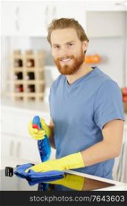 man with spray cleaner cleaning cooker at home kitchen