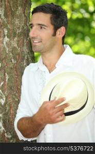 Man with straw hat leaning against tree