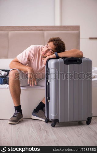 Man with suitcase in bedroom waiting for trip 