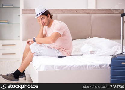 Man with suitcase in bedroom waiting for trip 