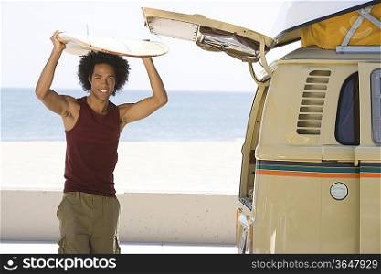 Man with surfboard by camper van