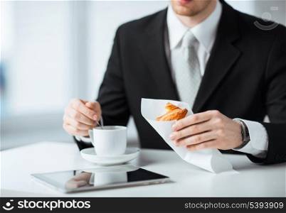man with tablet pc, cup of coffee and croissant