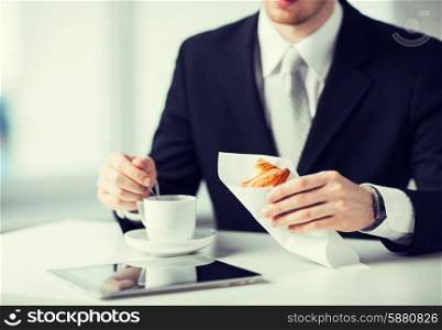 man with tablet pc, cup of coffee and croissant