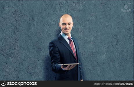 Man with tablet pc. Young businessman against grey background holding tablet pc
