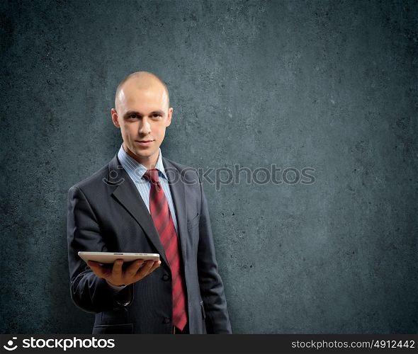 Man with tablet pc. Young businessman against grey background holding tablet pc