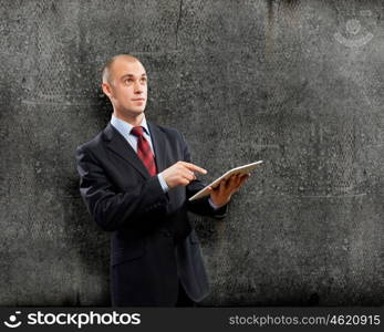 Man with tablet pc. Young businessman against grey background using tablet pc