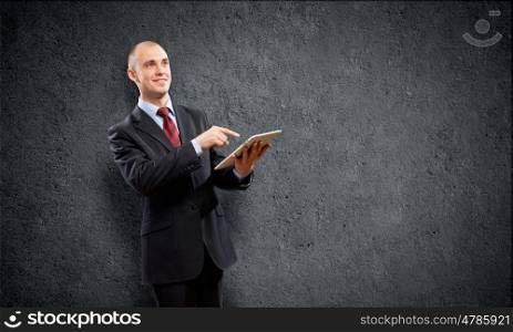 Man with tablet pc. Young businessman against grey background using tablet pc
