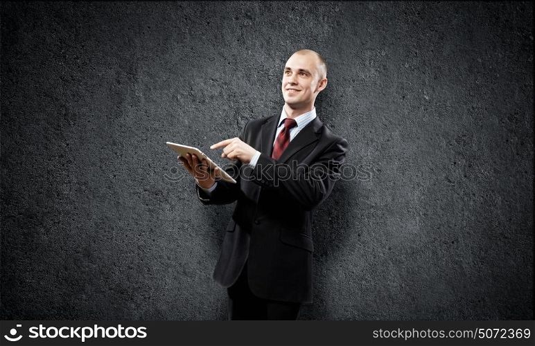 Man with tablet pc. Young businessman against grey background using tablet pc