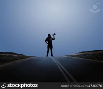 Man with trumpet. Silhouette of man at night screaming in megaphone