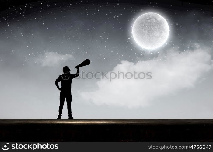 Man with trumpet. Silhouette of man at night screaming in megaphone