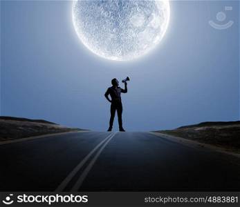 Man with trumpet. Silhouette of man at night screaming in megaphone