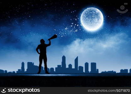 Man with trumpet. Silhouette of man screaming in trumpet at night