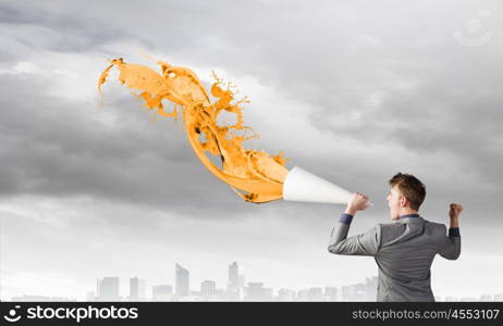 Man with trumpet. Young businessman screaming emotionally in paper trumpet