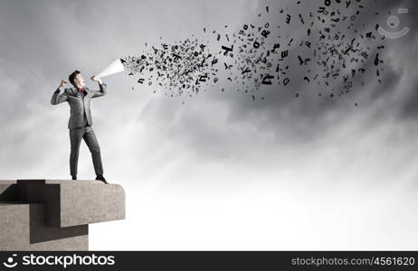 Man with trumpet. Young businessman screaming emotionally in paper trumpet