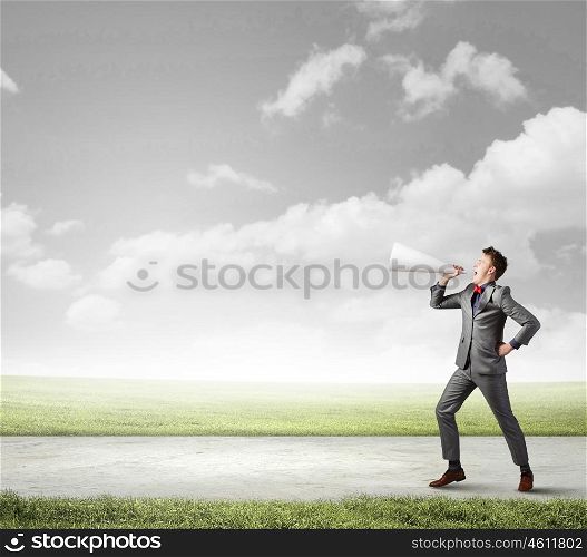 Man with trumpet. Young businessman screaming emotionally in paper trumpet