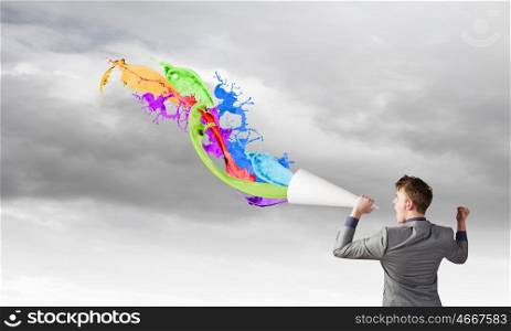 Man with trumpet. Young businessman screaming emotionally in paper trumpet