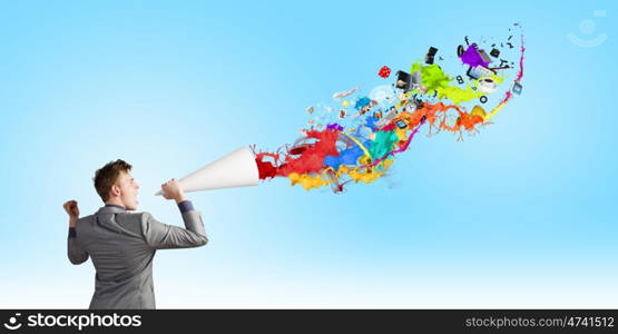 Man with trumpet. Young businessman screaming emotionally in paper trumpet